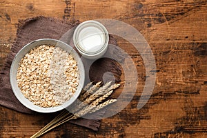 Rolled oats, oat flakes and oat milk on wooden table