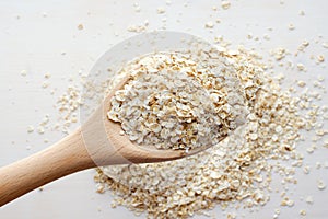 Rolled oats in wooden spoon over white background