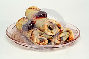 Rolled pancakes with strawberry jam on a glass plate