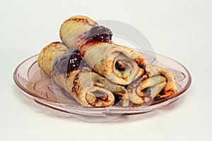 Rolled pancakes with strawberry jam on a glass plate photo