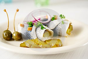 Rolled pickled herring, also called rollmops with red onions, gherkins and capers as a hangover meal, close up shot, copy space