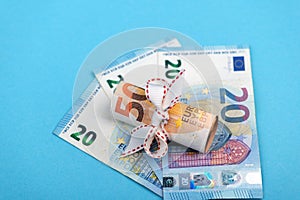 Rolled into a roll of 50 euros on a light blue background of 20 euro banknotes