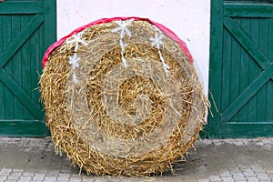 Rolled straw decorated with white snow crystals at rural animal farm as a christmas background
