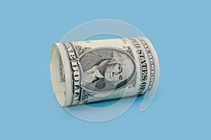 Rolled up 1 dollar bill on blue isolated background. roll of American banknotes, roll of US dollar bills. Side view .