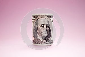 Rolled up bill on a pink background. 100 dollars. Money