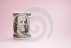 Rolled up bill on a pink background. 100 dollars. Money