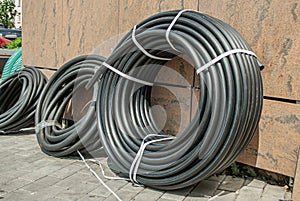 A rolled up black industrial rubber hose tied with rope on the street