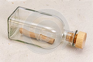 A rolled-up old paper note in a glass bottle with a cork on a light background. Concept: sea mail, a message from an island, a req