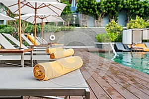 Rolled up orange towel on a sun lounger background of pool in re