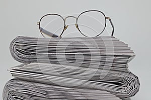 Rolled up stack of fresh newspapers and glasses, news, printed background