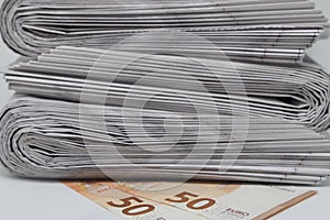 Rolled up stack of newspapers, banknotes stuck between newspapers, news, fake news, corrupt press.