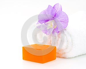 Rolled white towel, soap and orchid