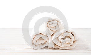 Rolled white towels on white wooden table isolated on white background. Copy space and top view. Bathroom objects for shower body