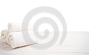 Rolled white towels on white wooden table isolated on white background. Copy space and top view. Bathroom objects for shower body