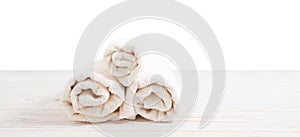 Rolled white towels on white wooden table  on white background. Copy space and top view. Bathroom objects for shower body