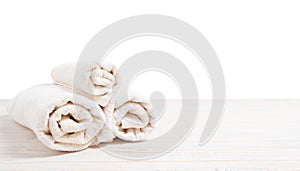 Rolled white towels on white wooden table  on white background. Copy space and top view. Bathroom objects for shower body