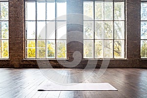 Rolled yoga pilates rubber mat inside gym studio on wooden floor background photo