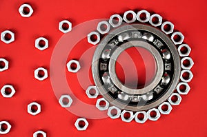 Roller bearing and metal screws on a red background.