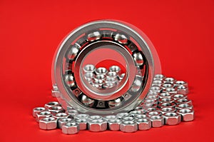 Roller bearing and metal screws on a red background.