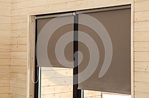 Roller Blinds on Window on Wooden Wall. Modern sunproof blinds grey pastel color