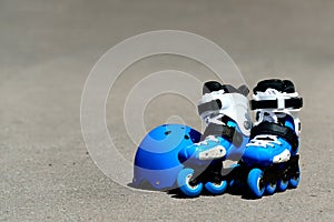 Roller inline skates with helmet in skate park on gray asphalt background