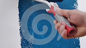 Roller painting of a white wall with blue paint