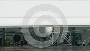 Roller shutter door and plane in hangar background. Business jet airplane is in hangar. Private corporate jet parked in