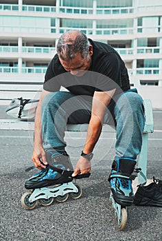 Roller skate, tie shoes and senior man in city for sports, adventure and fitness hobby outdoors. Exercise, weekend and