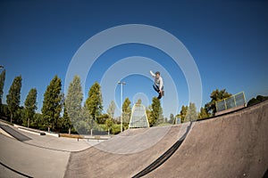 A roller skater jumps a ramp doing a trick in a skate park