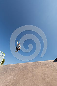 A roller skater jumps a ramp doing a trick in a skate park