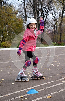 Roller skating  happy little girl in park rollerblading on inline skates. Caucasian girl in outdoor activities