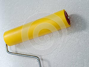 Roller for smoothing wallpaper yellow. Paint roller with a red handle and a yellow smooth nozzle on a light background