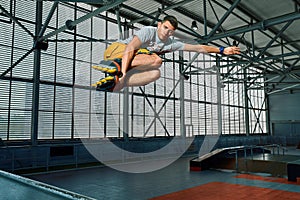 Rollerblader jump high from big air ramp performing trick. Indoors skate park equipment.