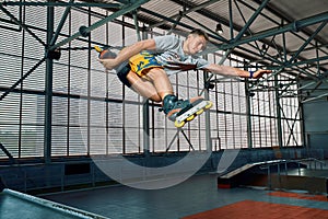 Rollerblader jump high from big air ramp performing trick. Indoors skate park equipment.