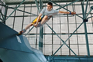 Rollerblader jump high from big air ramp performing trick. Indoors skate park equipment.