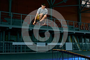 Rollerblader jump high from big air ramp performing trick. Indoors skate park equipment.