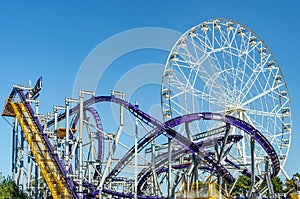 Rollercoaster and Ferris wheel against blue sky