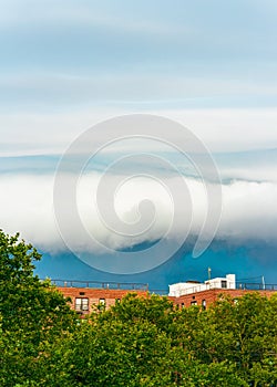 Rolling Clouds Over Urban Greenery and Rooftops. White cloud on blue pre-storm sky in New York, USA, background, weather