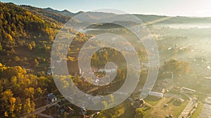 Rolling Fog at Sunrise over City in Mountains at Autumnal Foliage Colors