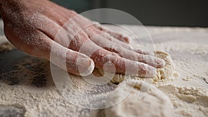 Rolling out dough close-up. A man rolls the dough on a wooden table with a wooden rolling pin.
