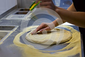 Rolling out pizza bases from dough with pizza hands