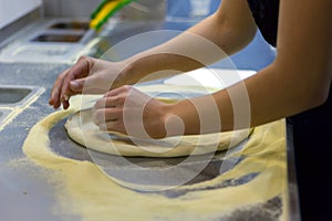 Rolling out pizza bases from dough with pizza hands