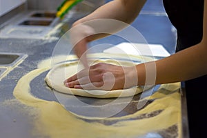Rolling out pizza bases from dough with pizza hands