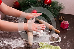 Rolling pin child rolls dough for christmas cookies