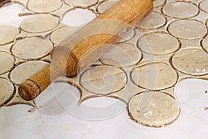 Rolling pin with dough on kitchen table. Preparing dough round t