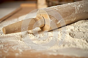 Rolling pin on pastry board sprinkled with flour on wooden  table