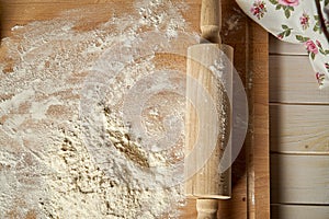 Rolling pin on pastry board sprinkled with flour on wooden  table