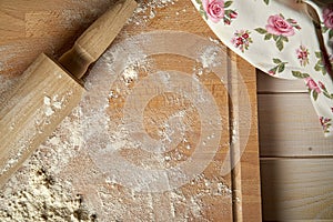 Rolling pin on pastry board sprinkled with flour on wooden  table