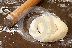 Rolling pin and raw dough prepared for donuts