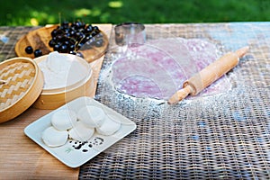 a rolling pin is on a table next to a bowl of blueberries and a bowl of flour. Mochi asian dessert